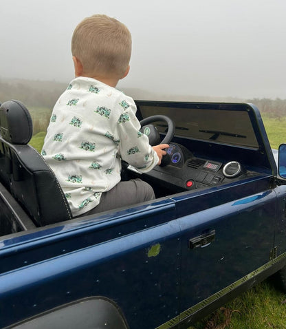 child in driving seat of toy landrover wearing a landrover top